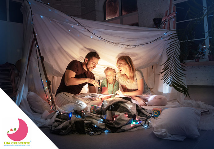 Crianças dentro de uma tenda improvisada a ler livros com luz suave