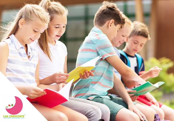 Crianças sentados num parque a ler livros juntos